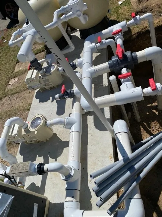 Pool pumps, filters and red-handled valves connected with PVC pipe